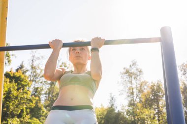 Barfiks çekmek açık spor zeminde yapıyor genç güzel kız