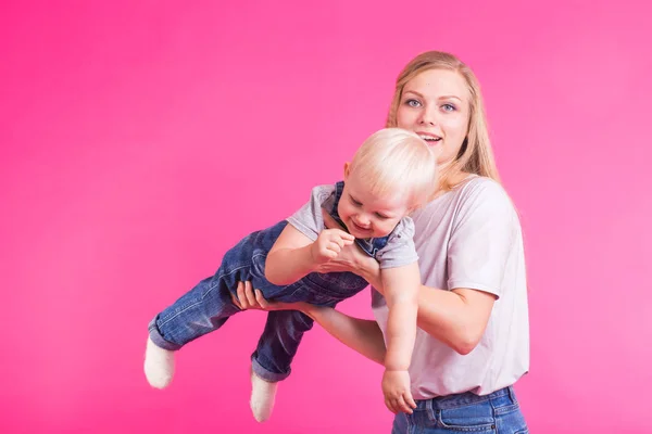 Jovem mãe e filha se divertindo juntos no fundo rosa — Fotografia de Stock