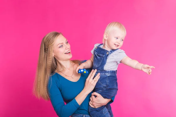 Menina feliz e sua mãe se divertindo sobre fundo rosa — Fotografia de Stock