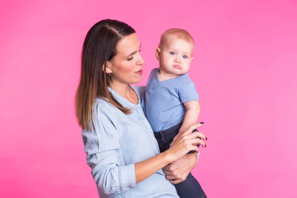 Feliz jovem mãe com um bebê criança no fundo rosa — Fotografia de Stock