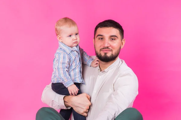 Glücklicher Vater mit einem kleinen Sohn auf rosa Hintergrund — Stockfoto