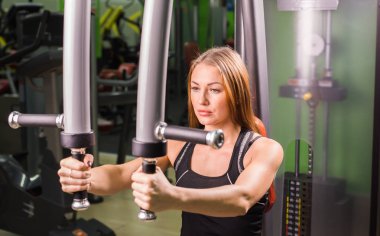 Beyaz fitness kadın spor salonunda kelebek makinede çalışıyor