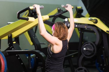 Spor, fitness, yaşam tarzı ve insanlar kavramı - güzel kadın kas spor salonu makinede esneme