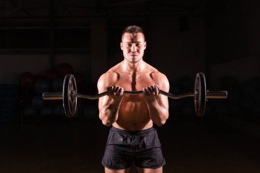kas genç adam koyu arka plan üzerinde ağırlık kaldırma