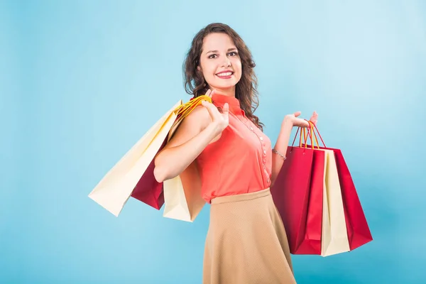 Retrato de mulher sorridente feliz segurar saco de compras. Modelo feminino isolado estúdio azul fundo . — Fotografia de Stock