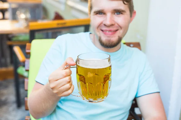 Молодий чоловік тримає велике пиво і дивиться на камеру — стокове фото