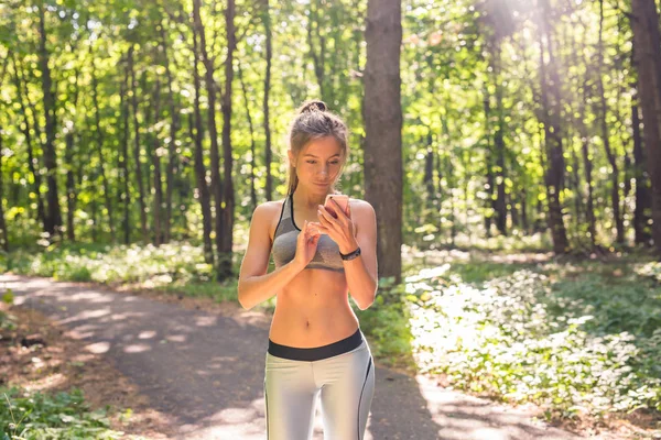 Chica activa usando el rastreador de fitness reloj inteligente trotar en la naturaleza de verano al aire libre mirando los datos de salud durante la actividad deportiva — Foto de Stock