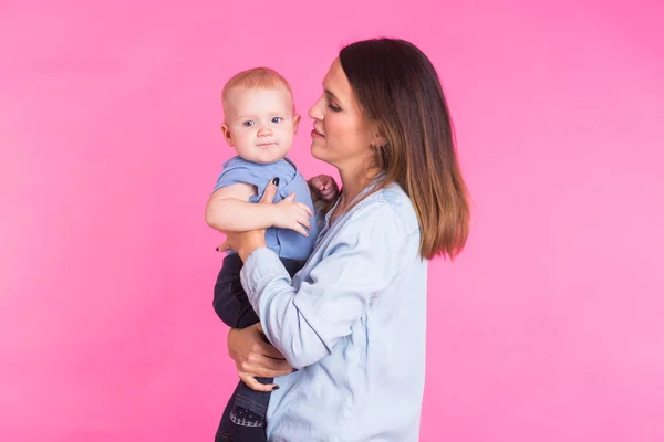 Madre cariñosa jugando con su bebé sobre fondo rosa — Foto de Stock