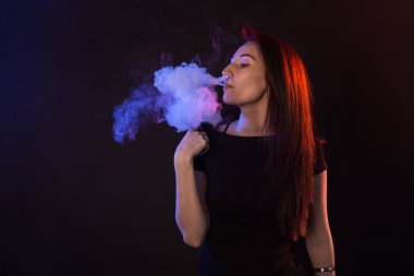 Genç kadın sigara elektronik sigara koyu arka plan üzerinde