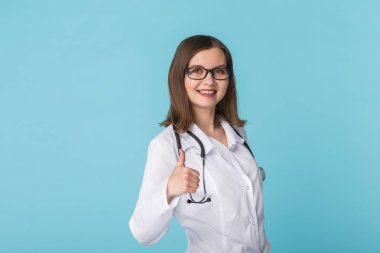 Tıp doktoru başparmak kopya alanı ile mavi arka plan üzerinde gösterilen stetoskop ile gülümseyen