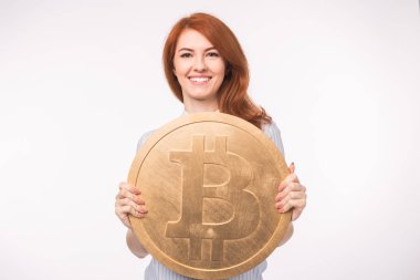Büyük bitcoin beyaz arka plan üzerinde tutan Kızıl saçlı kadın. Cryptocurrency yatırım kavramı.