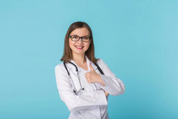 Retrato de mulher médico mostrando polegares para cima sobre fundo azul — Fotografia de Stock