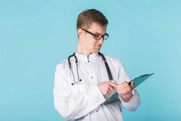 Medical doctor writing prescription over blue background. — Stock Photo, Image