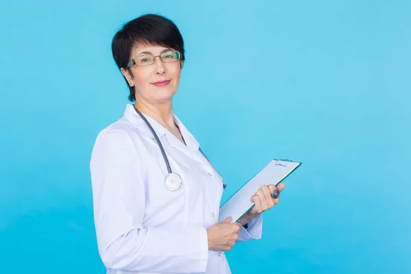 Medical doctor writing prescription over blue background with copy space.