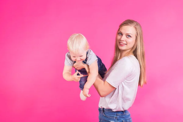 Familia divertida sobre fondo rosa. Madre y su hija. Mamá y el niño se están divirtiendo . — Foto de Stock