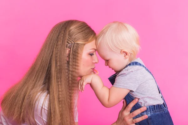 Menina feliz e sua mãe se divertindo sobre fundo rosa — Fotografia de Stock