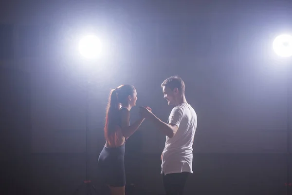 Dançarinos habilidosos se apresentando na sala escura sob a luz do concerto e fumaça. Casal sensual realizando uma dança contemporânea artística e emocional — Fotografia de Stock