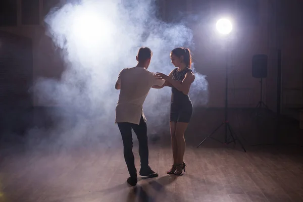 Bailarines hábiles actuando en la sala oscura bajo la luz del concierto y el humo. Pareja sensual realizando una danza contemporánea artística y emocional — Foto de Stock