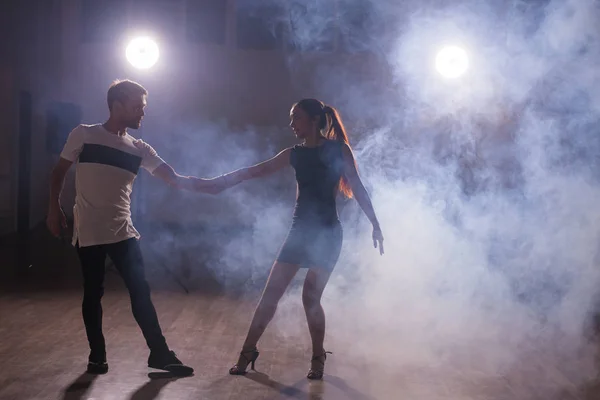 Искусные танцоры выступают в темной комнате под концертным светом и дымом. Чувственная пара, исполняющая художественный и эмоциональный современный танец — стоковое фото