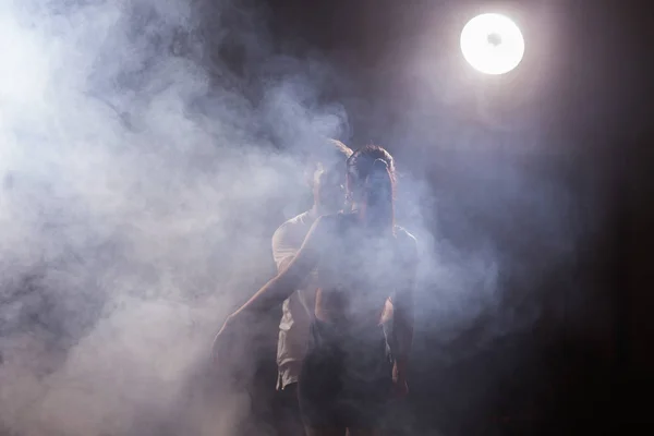 Abili ballerini che si esibiscono nella stanza buia sotto la luce e il fumo del concerto. Coppia sensuale che esegue una danza contemporanea artistica ed emotiva — Foto Stock