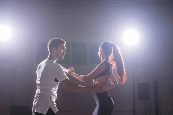 Bailarines hábiles actuando en la sala oscura bajo la luz del concierto y el humo. Pareja sensual realizando una danza contemporánea artística y emocional — Foto de Stock