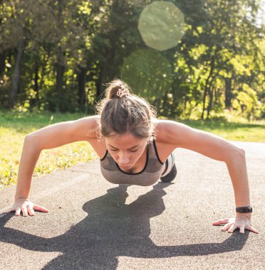 Genç kadın açık havada şınav yaparak egzersiz yerleştirmek
