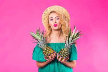 Bir ananas pembe bir arka plan üzerinde tutan mutlu genç kadın. Yaz, diyet ve tatil kavramı