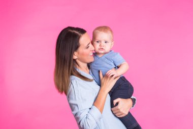 Sevgi dolu bir anne, pembe arka plan bebek oğlu ile oynamak