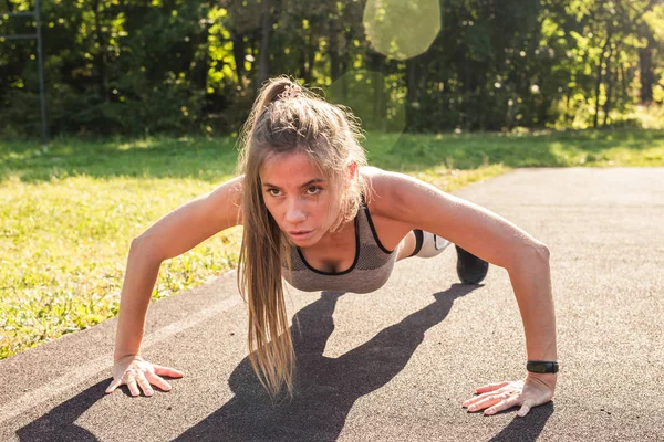 Mujer en forma joven haciendo ejercicio haciendo flexiones al aire libre — Foto de Stock