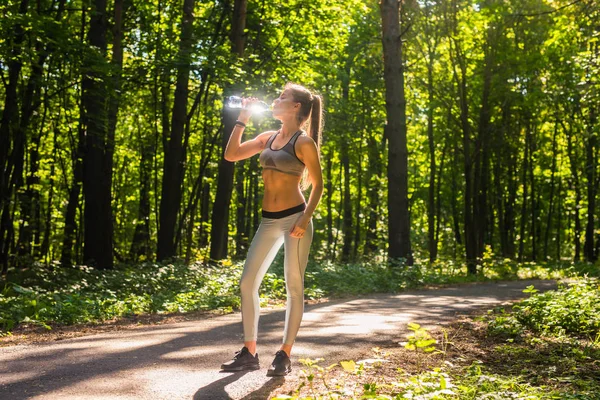 Jovem mulher bebendo água depois de correr ao ar livre — Fotografia de Stock