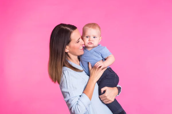 Madre cariñosa jugando con su bebé sobre fondo rosa — Foto de Stock