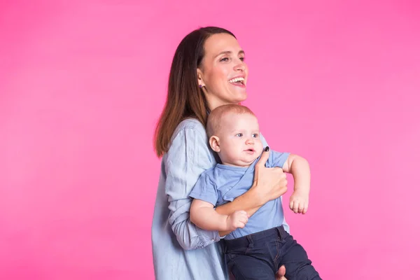 Madre cariñosa jugando con su bebé sobre fondo rosa — Foto de Stock
