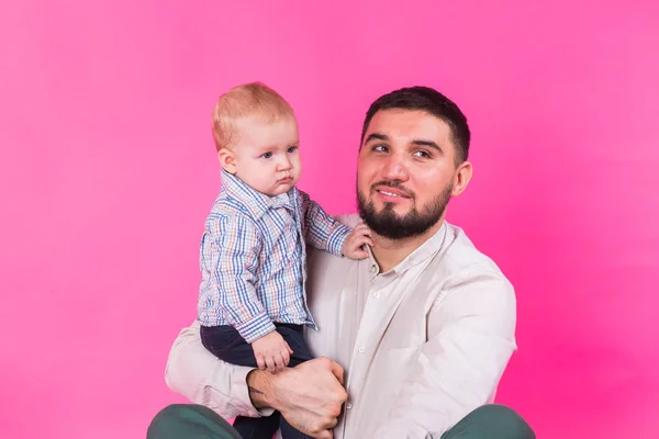 Glücklicher Vater mit einem kleinen Sohn auf rosa Hintergrund — Stockfoto