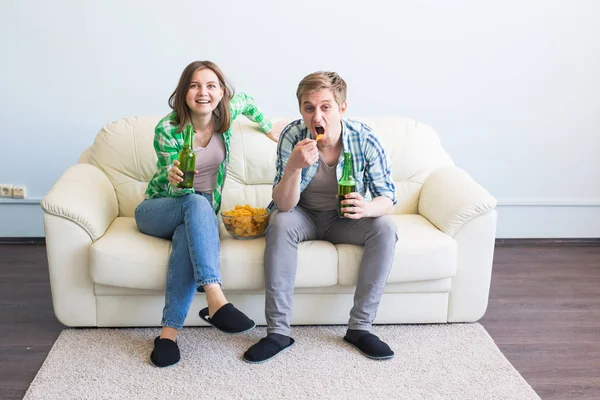 テレビでスポーツの試合を見ながらソファに座っている友人のカップル — ストック写真