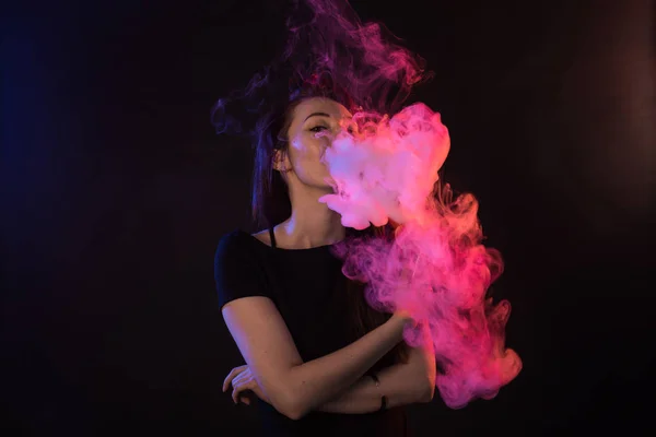 Joven mujer fumar cigarrillo electrónico sobre fondo oscuro — Foto de Stock