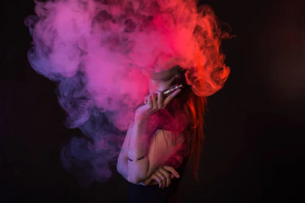 Jeune femme fumant cigarette électronique sur fond sombre — Photo