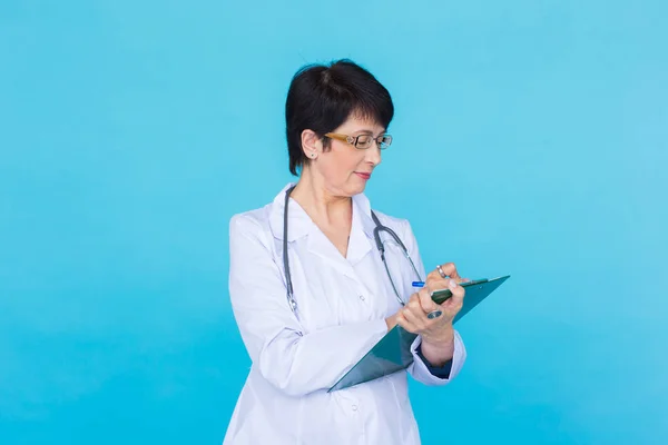 Portret z kobiece kobieta lekarz pisania na Schowka nad niebieskim tle — Zdjęcie stockowe