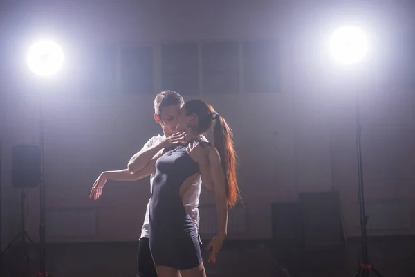 Επιδέξιοι χορευτές εκτελούν στο σκοτεινό δωμάτιο κάτω από τη συναυλία του φωτός και του καπνού. Αισθησιακό ζευγάρι εκτελώντας μια καλλιτεχνική και συναισθηματική σύγχρονου χορού — Φωτογραφία Αρχείου