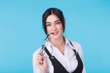 Mavi arka plan üzerinde kameraya bakarak gülümseyen genç güzel şirin neşeli öğrenci kız portresi