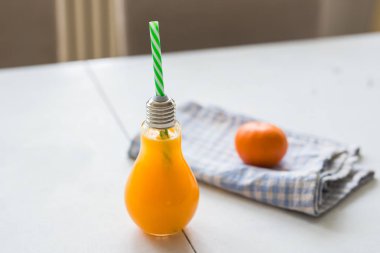 Beyaz masa üzerinde bir tüp cam portakal suyu.