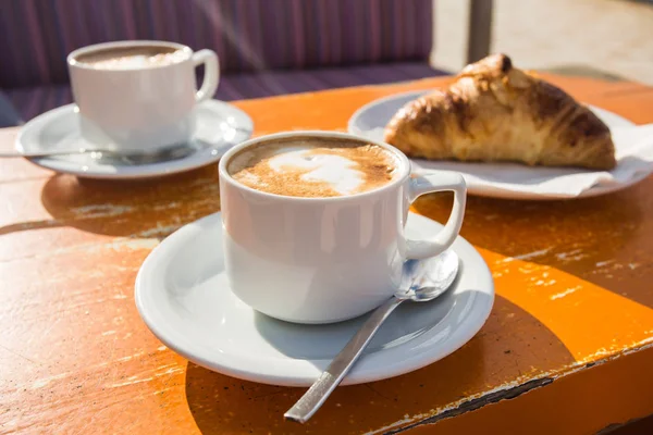 Dva šálky povzbuzující cappuccino a croissanty k snídani — Stock fotografie