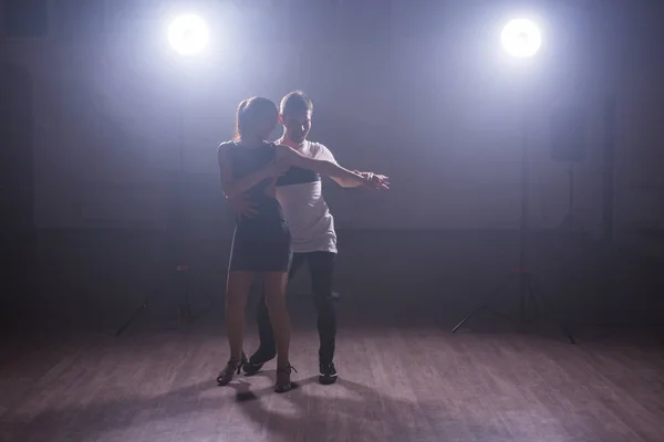 Geschickte Tänzer, die im dunklen Raum unter dem Licht und Rauch des Konzerts auftreten. sinnliches Paar, das einen künstlerischen und emotionalen zeitgenössischen Tanz aufführt — Stockfoto