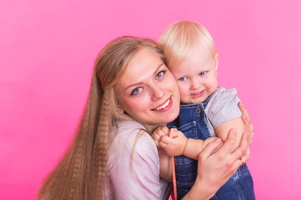 Mladá matka a dcera baví společně na růžové pozadí — Stock fotografie