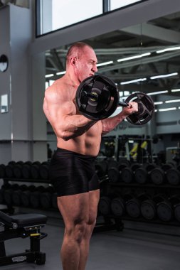 Spor salonunda yakışıklı vücut geliştirmeci adamla büyük kaslar