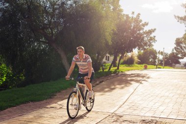 Yakışıklı genç adam Bisiklet ve kask Park güneşli