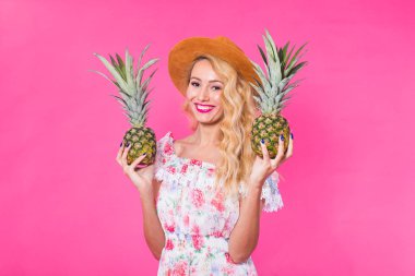 Bir ananas pembe bir arka plan üzerinde tutan mutlu genç kadın. Yaz, diyet ve tatil kavramı