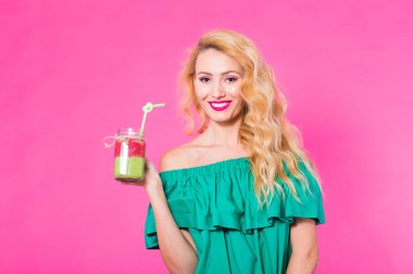 Pembe bir arka plan üzerinde yeşil güler yüzlü genç güzel kadın