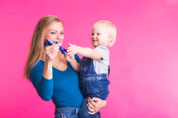 Menina feliz e sua mãe se divertindo sobre fundo rosa — Fotografia de Stock