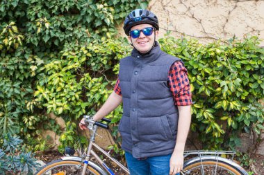 Genç adam gülümseyen bir bisiklet içinde belgili tanımlık bahçe tutun.