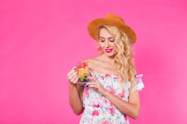 Meyve kavanoz boşaltmak ile pembe arka plan üzerinde olan güzel kadın